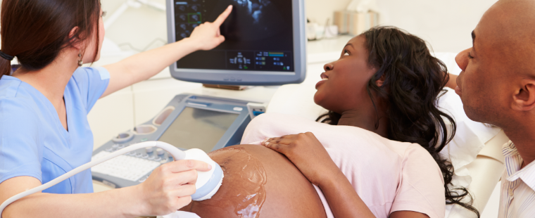 Femme enceinte et son partenaire regardant un moniteur avec une technologue spécialisée en échographie